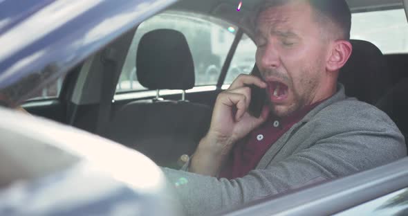 Man Speaking on the Phone at Car Seat Sneezing and Wipes His Nose with a Napkin