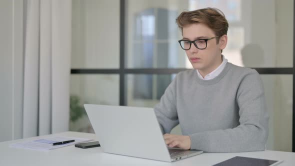 Young Man Working on Laptop in Modern Office