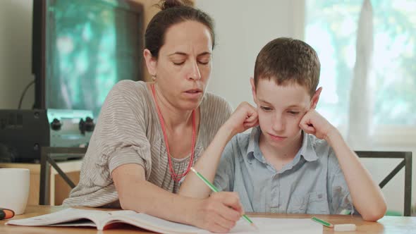 Mother helping her son to do his homework at home