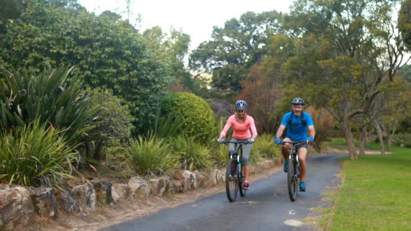 Couple interacting while riding bicycle on road