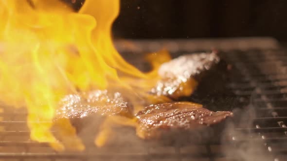 Meat Steak on the Grill. Lots of Fire. Extreme Slow Motion. Flaming Beef Steak Close-up. The Cook Is