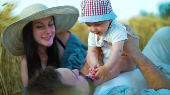 Happy family with baby having fun during picnic in wheat field