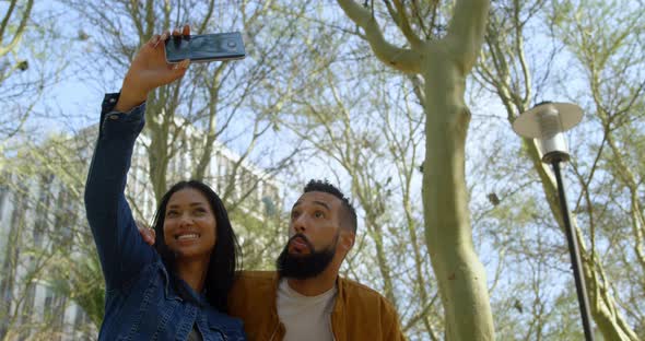 Low angle view of young mixed-race couple clicking selfie with mobile phone in the city 4k