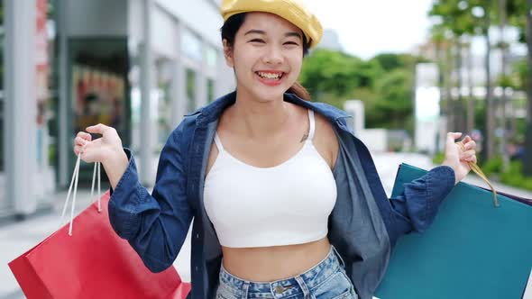 Smiling young Asian woman with shopping colour bags