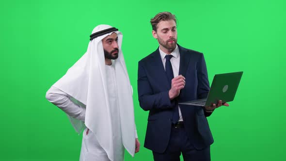 Businessman Uses a Laptop and Communicate with a Arab Business Partner in a White Kandura Discussing