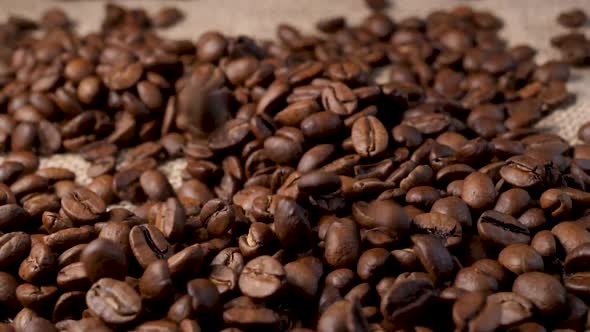 Roasted coffee beans with smoke. Slow motion of arabica coffee seeds falling.