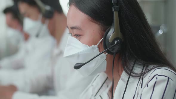Close Up Of An Asian Woman Call Centre Agent Wearing Mask While Speaking To Customer