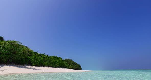 Wide flying copy space shot of a white paradise beach and turquoise sea background in vibrant 4K