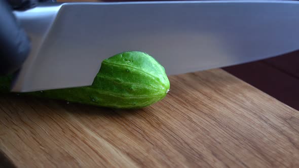 Cutting a Japanese Cucumber with a Knife on a Wooden Cutting Board