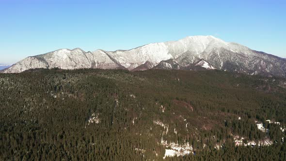 Aerial pan of Postavarul Massif, Romania in winter, part of Carpathian Mountains.