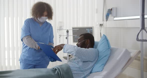 Afroamerican Patient Lying in Hospital Bed and Signing Agreement on Operation