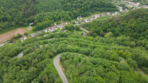 Drone discovering a picturesque mountain road with numerous hairpin bends in the lush hills of the m