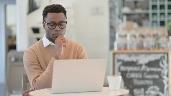 Creative African Man Thinking While Using Laptop in Cafe