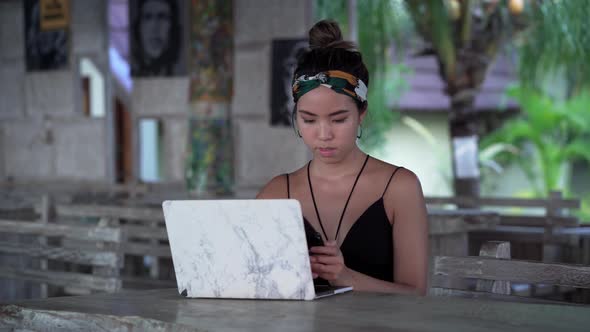 Young freelancer girl typing on mobile at restaurant outside, Bali