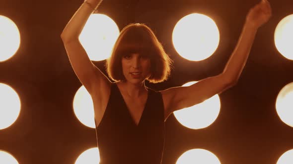 Beautiful woman dancing in front of a wall of lights