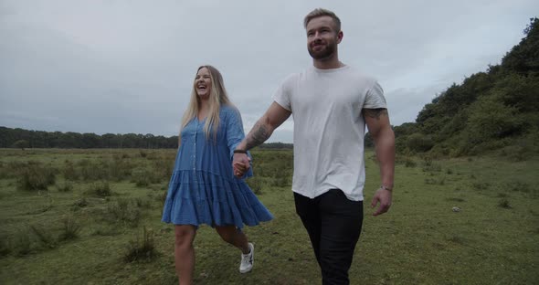 Blonde Woman and Buffed Man Walking Hand in Hand