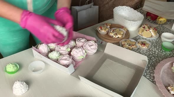 A Woman Is Packing Marshmallows Into A Box.