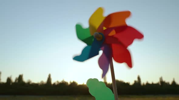 Colorful Paper Windmill Spinning in the Blue Sky Against the Skyline with Trees