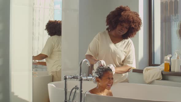 African American Mother Washing Kid in Bathroom