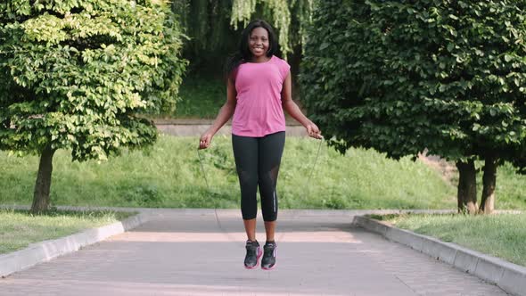 African American Woman Makes a Jump Rope Routine in a City Park