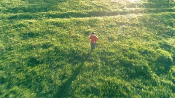 Flight Over Sporty Man Running at Perfect Green Grass Rural Meadow Offroad. Sunset in Mountain