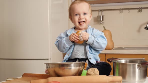 Portrait of Cute Smiling Baby Boy Eating Fresh Bread and Playing Wth Flour on Kitchen
