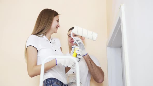 Young Happy Couple Decorating Room  Painting Wall with Paint Roller