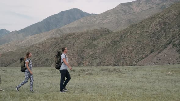 A Group of Tourists Walk Along a Trail in the Mountains in Summer Weather.