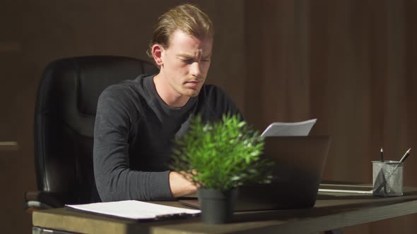 Young Businessman Sit in the Office at the Table Near Computer, Working at Documents