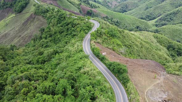 Aerial view of mountain road through tropical forest in countryside by drone