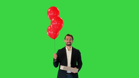 Handsome Guy in an Elegant Suit with a Gift Box and Balloons Walking on a Green Screen Chroma Key