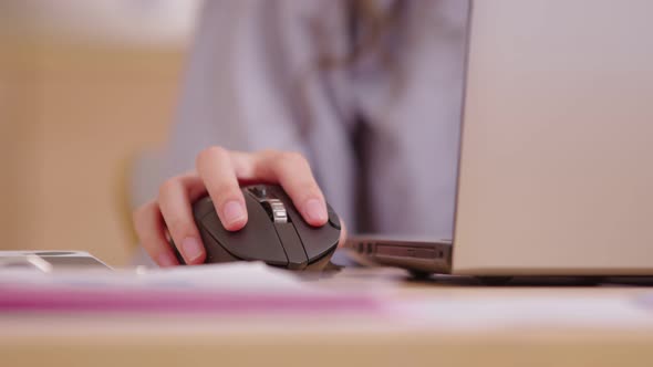 Close up of click black computer mouse on a work desk. Asian woman with curly hair working with a PC