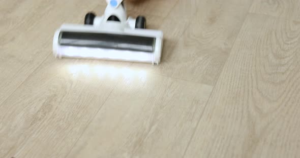 Unrecognizable female using modern vacuum cleaner to remove dust from floor