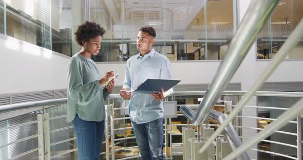 Video of diverse businessman and businesswoman talking on staircase