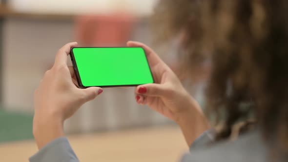 African Woman Looking at Smartphone with Green Chroma Key Screen