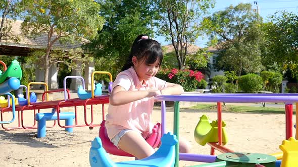 Cute Asian Girl Playing Carousel In The Park