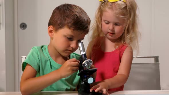 Boy Helps a Girl Look Through a Microscope