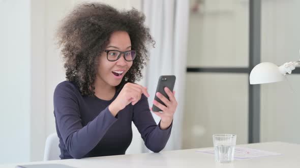 African Woman Celebrating Success While Using Smartphone