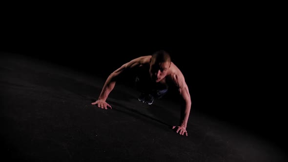 Young Pumped Man Doing Push Ups in the Dark Arena