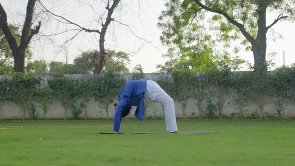 Wheel Yoga pose or Chakrasana is being done by an Indian man