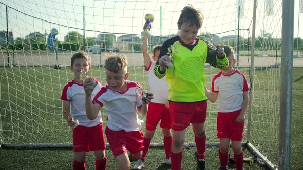 Junior Football Team Jumps Up Holding Trophies