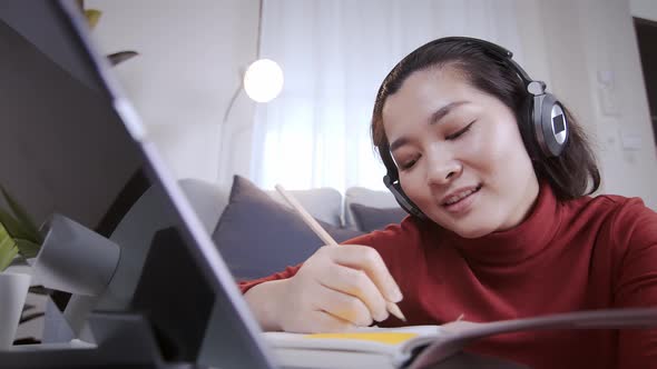 Businesswoman redshirt using a tablet with headphone for meeting online at home