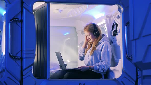 A Girl with a Laptop Closes the Door of a Capsule Hotel Room