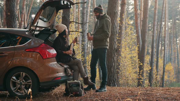 A Couple Is Drinking Coffee Near a Car in the Forest