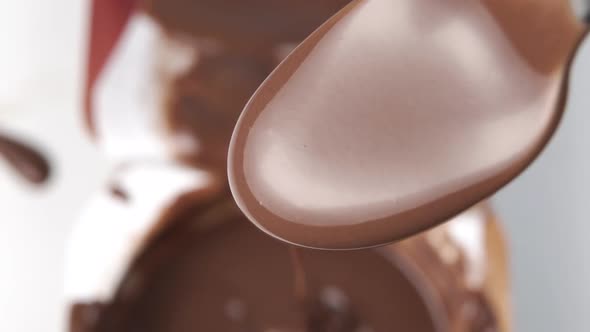 Full spoon of liquid chocolate close up. Pours in slow motion