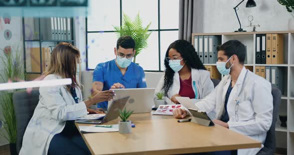 Medical Team in Medical Masks Finishing Joint Meeting in Boardroom and Putting hand