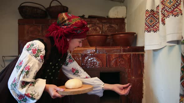 Young Woman in a Traditional Ukrainian Vyshyvanka Costume Puts Raw Bread Dough