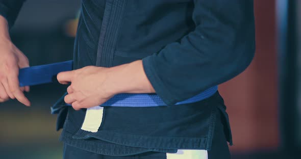 Male Judoka Ties a Kimono Belt Before Training