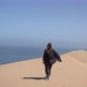 A Young Woman Walks Along Sandy Dunes on Seashore - VideoHive Item for Sale