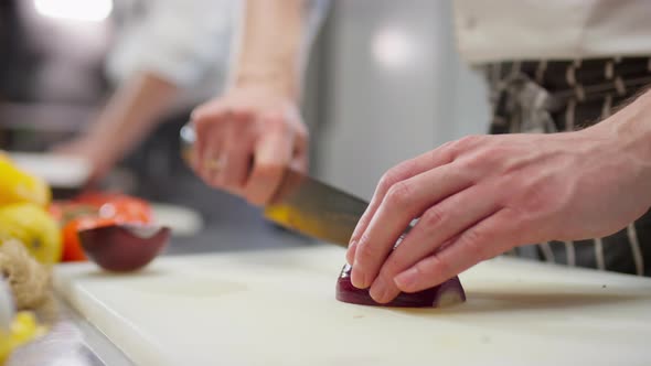 Hands of Chef Cutting Red Onion